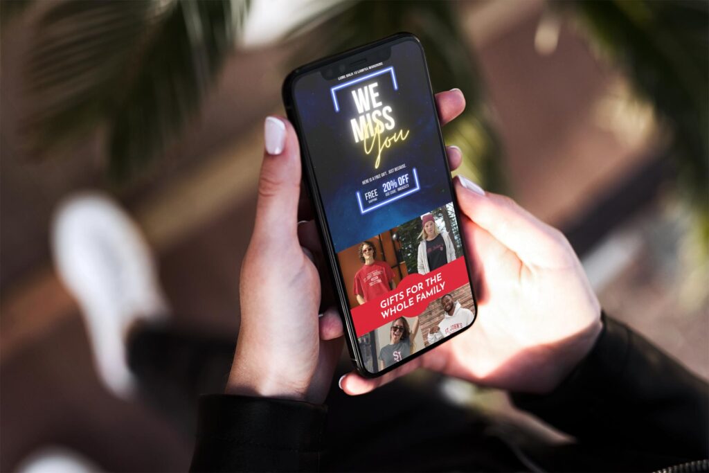 phone in the hands of a woman with a email on screen that says we miss you 20% off and gifts for the whole family