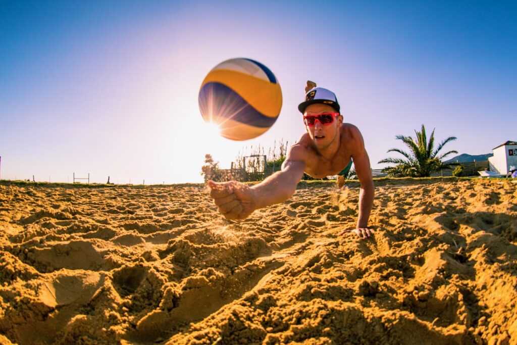 Volleyball player diving to save the ball from hitting the sand.