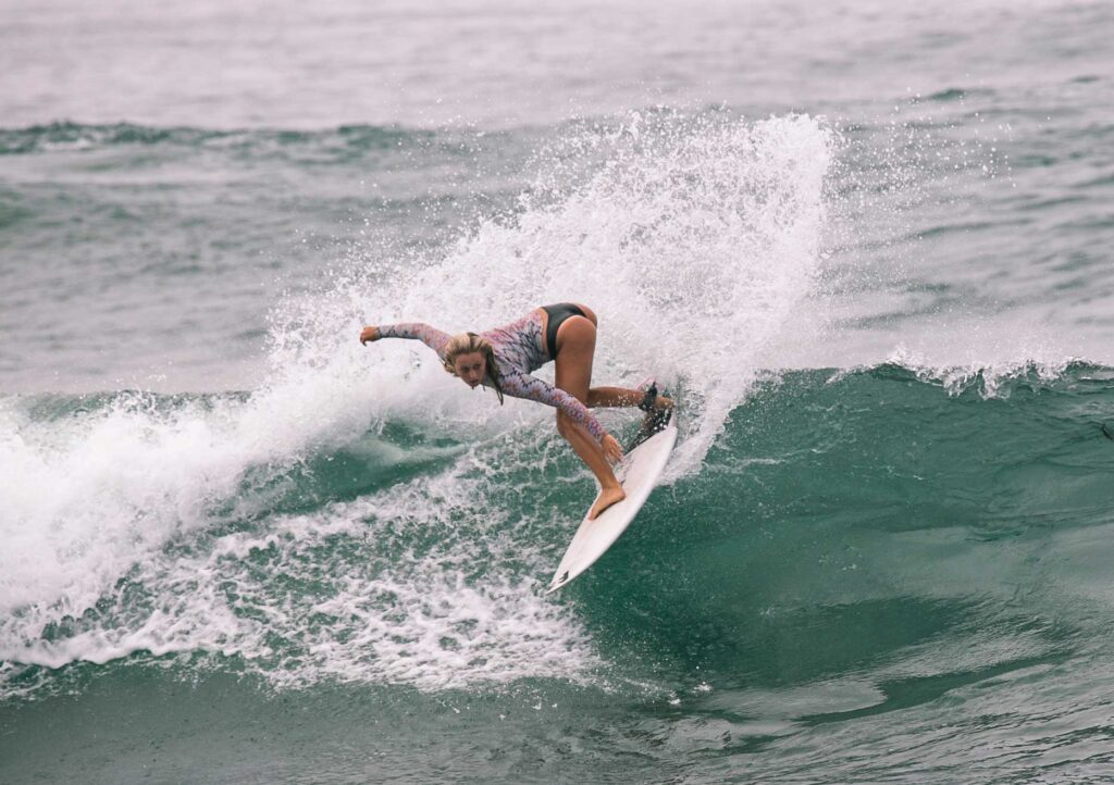 Female surfer creates a spray with a turn on a wave